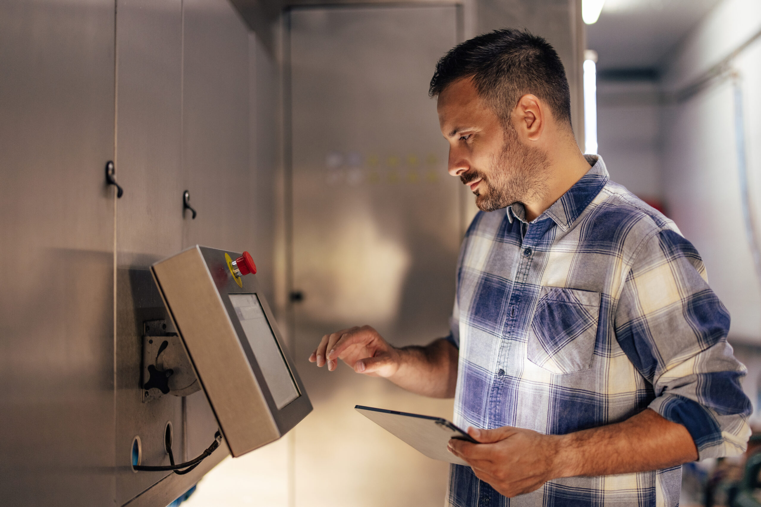 Adult man, checking the new software, on the machine, in the factory.